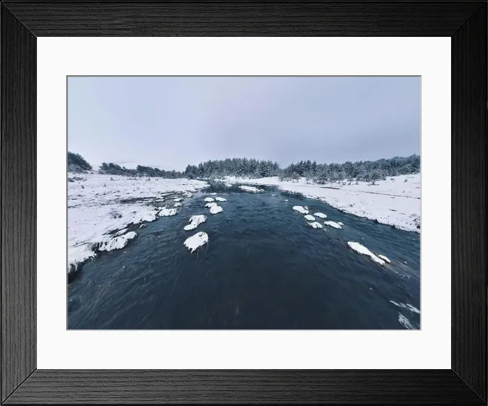Framed Print : An aerial view of a frozen river flowing through snow-covered forests on a cloudy sunset sky background Framed Print : An aerial view of a frozen river flowing through snow-covered forests on a cloudy sunset sky background