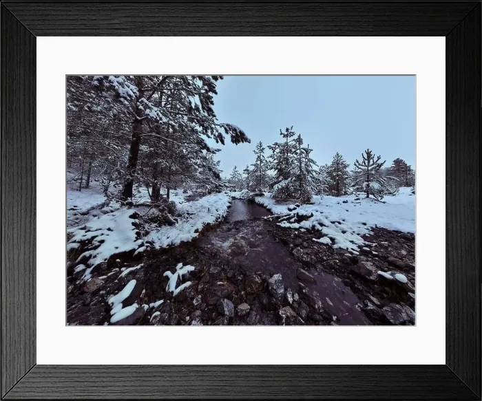 Framed Print : An aerial view of a frozen river flowing through snow-covered forests on a cloudy sunset sky background Framed Print : An aerial view of a frozen river flowing through snow-covered forests on a cloudy sunset sky background