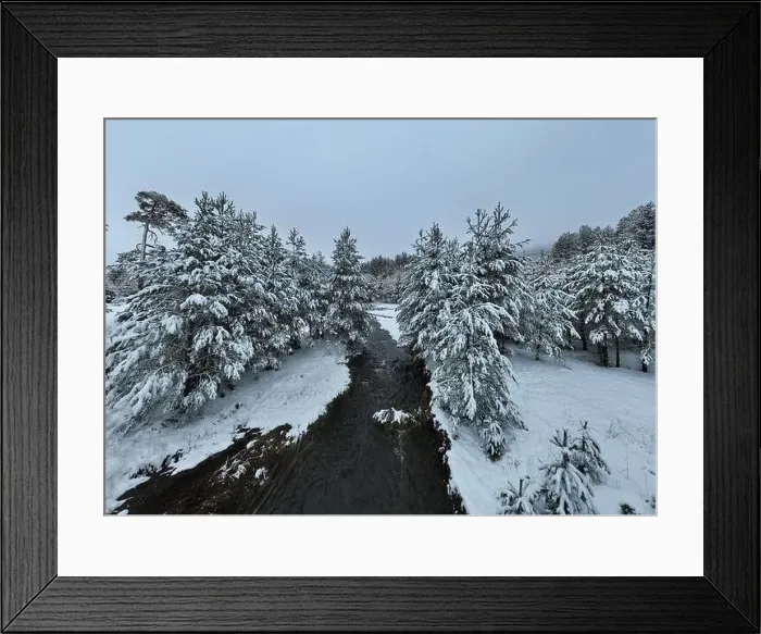 Framed Print : An aerial view of a frozen river flowing through snow-covered forests on a cloudy sunset sky background Framed Print : An aerial view of a frozen river flowing through snow-covered forests on a cloudy sunset sky background