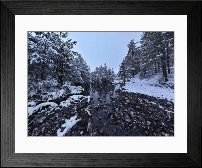 Framed Print : An aerial view of a frozen river flowing through snow-covered forests on a cloudy sunset sky background Framed Print : An aerial view of a frozen river flowing through snow-covered forests on a cloudy sunset sky background