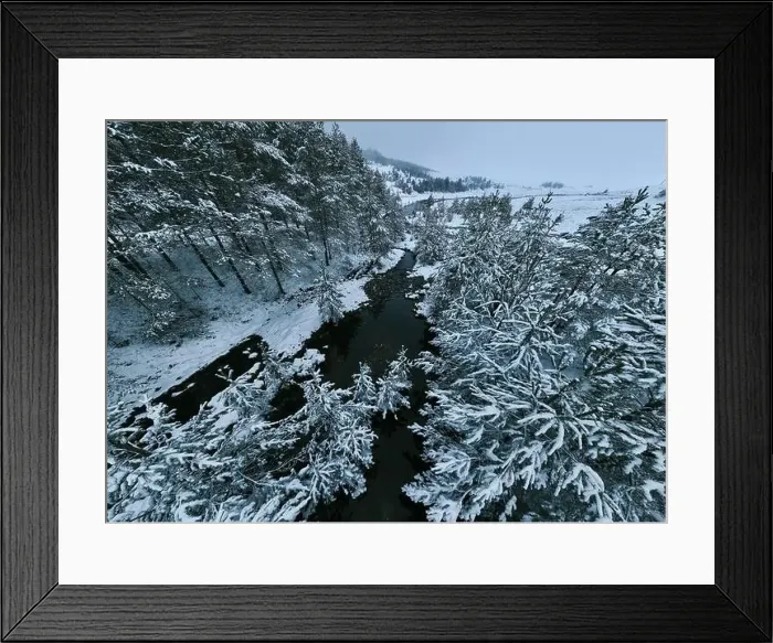 Framed Print : An aerial view of a frozen river flowing through snow-covered forests on a cloudy sunset sky background Framed Print : An aerial view of a frozen river flowing through snow-covered forests on a cloudy sunset sky background