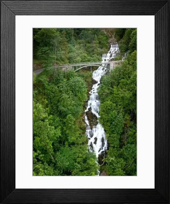 Framed Print : A bridge leads over a waterfall surrounded by green plants Framed Print : A bridge leads over a waterfall surrounded by green plants