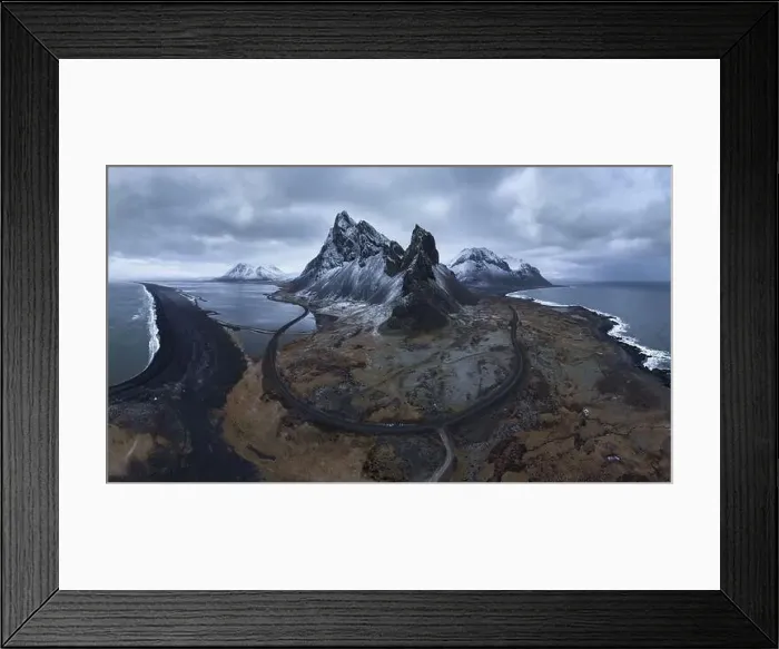Framed Print : Aerial view of asphalt road going between snowy mountain and blue ocean under cloudy sky in Eystrahorn Framed Print : Aerial view of asphalt road going between snowy mountain and blue ocean under cloudy sky in Eystrahorn