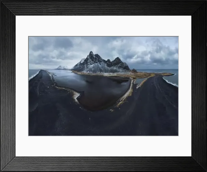 Framed Print : From above drone view of rocky mountains covered with snow located near waving seawater near black sand beach in Framed Print : From above drone view of rocky mountains covered with snow located near waving seawater near black sand beach in