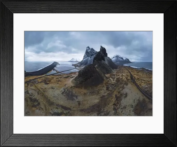 Framed Print : Aerial view of asphalt road going between snowy mountain and blue ocean under cloudy sky in Eystrahorn Framed Print : Aerial view of asphalt road going between snowy mountain and blue ocean under cloudy sky in Eystrahorn