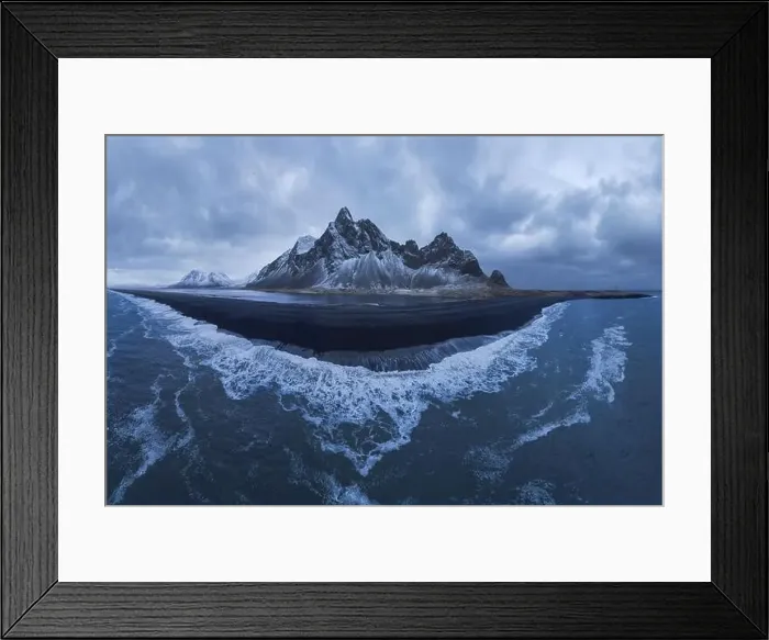 Framed Print : From above drone view of rocky mountains covered with snow located near waving seawater near black sand beach in Framed Print : From above drone view of rocky mountains covered with snow located near waving seawater near black sand beach in