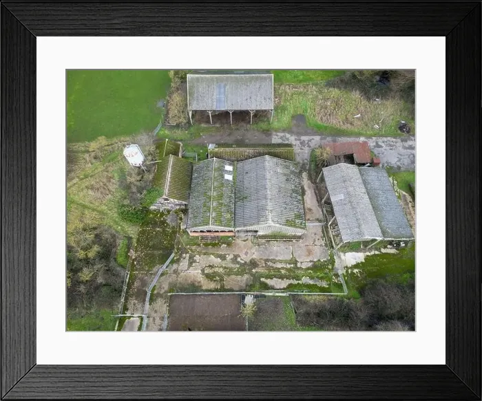 Framed Print : Aerial view of derelict farm buildings including hay barns and cow milking parlours. A grain silo is on the left Framed Print : Aerial view of derelict farm buildings including hay barns and cow milking parlours. A grain silo is on the left