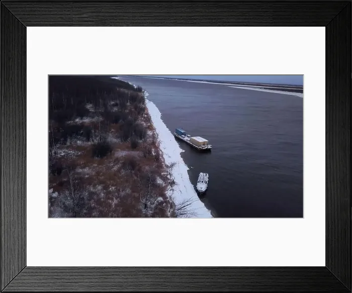 Framed Print : Winter frozen river. Clip.Cargo boats and bare trees on the shore taken from a bird's-eye view. High quality 4k footage Framed Print : Winter frozen river. Clip.Cargo boats and bare trees on the shore taken from a bird's-eye view. High quality 4k footage