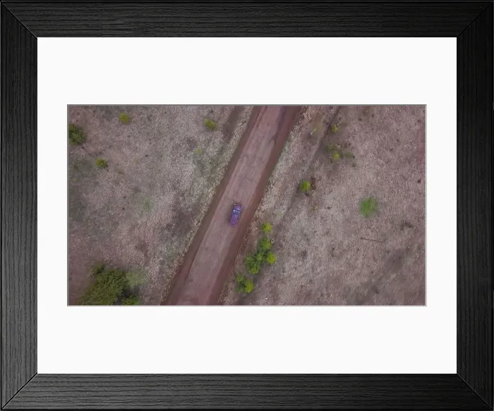 Framed Print : Aerial view of a rural road in the middle of green endless meadows Framed Print : Aerial view of a rural road in the middle of green endless meadows