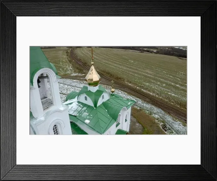 Framed Print : Aerial view of a white and green church with a golden cross and bell. Clip. Green field covered by snow Framed Print : Aerial view of a white and green church with a golden cross and bell. Clip. Green field covered by snow