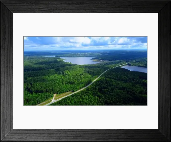 Framed Print : Aerial view of a narrow road becoming a bridge above the long river. Clip. Green forest and blue cloudy sky Framed Print : Aerial view of a narrow road becoming a bridge above the long river. Clip. Green forest and blue cloudy sky