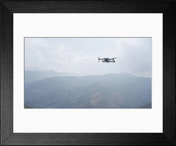 Framed Print : Drone quad copter against mountain in morning haze. Action. Video shooting of forested hills Framed Print : Drone quad copter against mountain in morning haze. Action. Video shooting of forested hills