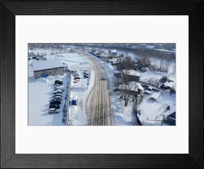 Framed Print : Aerial view of a countryside rural road covered by snow. Clip. Flying above rural road and a village Framed Print : Aerial view of a countryside rural road covered by snow. Clip. Flying above rural road and a village