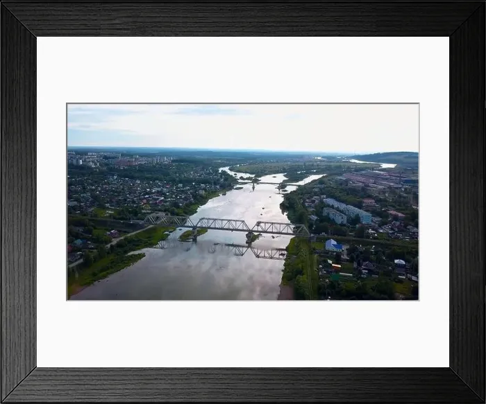 Framed Print : Aerial view of the city and a wide river with a bridge. Clip. Flying above summer city on a bright sky background Framed Print : Aerial view of the city and a wide river with a bridge. Clip. Flying above summer city on a bright sky background