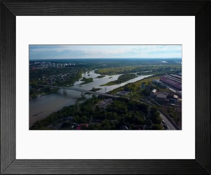 Framed Print : Aerial view of the city parts connected by the bridge. Clip. Wide river flowing along green vegetation and buildings Framed Print : Aerial view of the city parts connected by the bridge. Clip. Wide river flowing along green vegetation and buildings