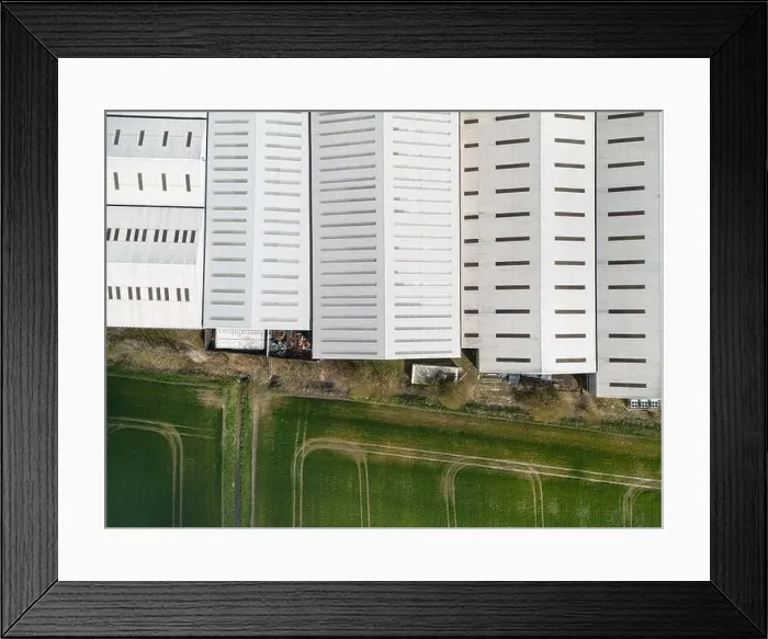 Framed Print : Drone top down view of a large warehouse facility seen at the edge of an arable field in a rural English location Framed Print : Drone top down view of a large warehouse facility seen at the edge of an arable field in a rural English location