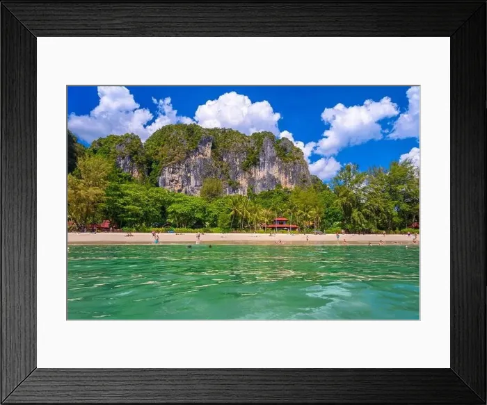 Framed Print : Bungalow house with red roof among coconut palms near the cliffs with people sunbathing