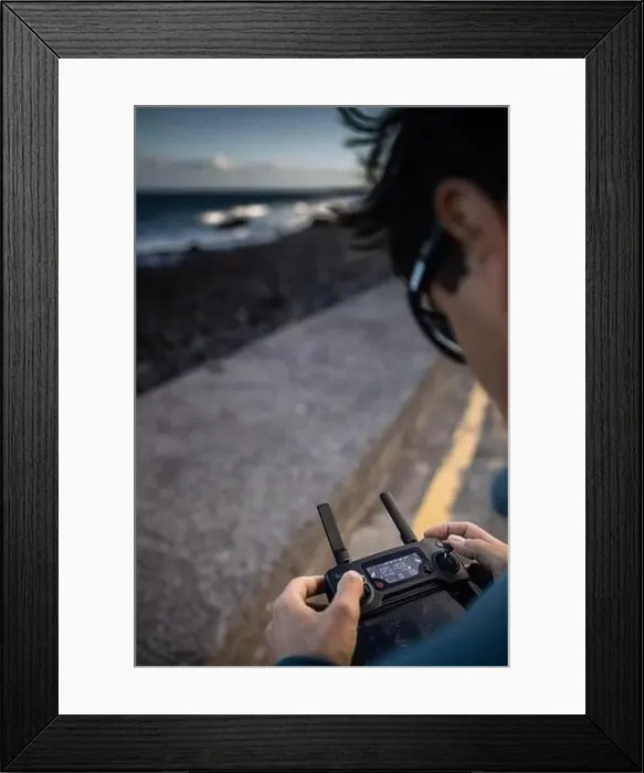 Framed Print : Drone pilot in action, taking aerial photos and capturing footage of waves crashing on a beach