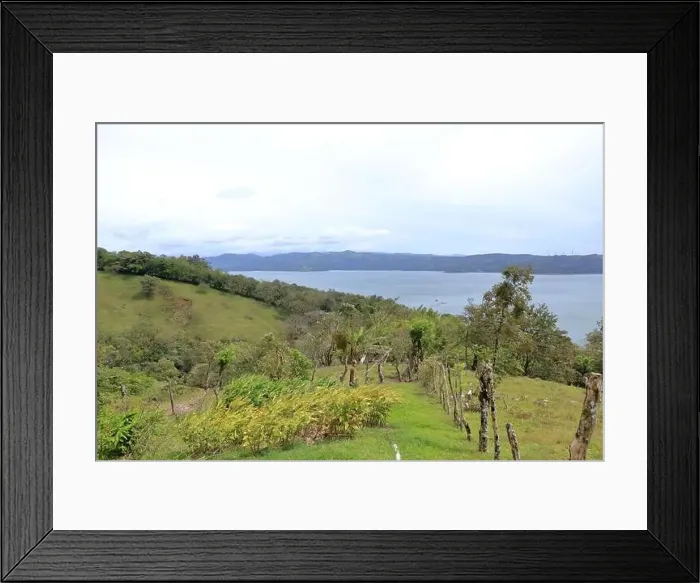 Framed Print : a Scenic view of lush green trees growing on hilly terrain against cloudy sky with lake arenal in costa rica Framed Print : a Scenic view of lush green trees growing on hilly terrain against cloudy sky with lake arenal in costa rica