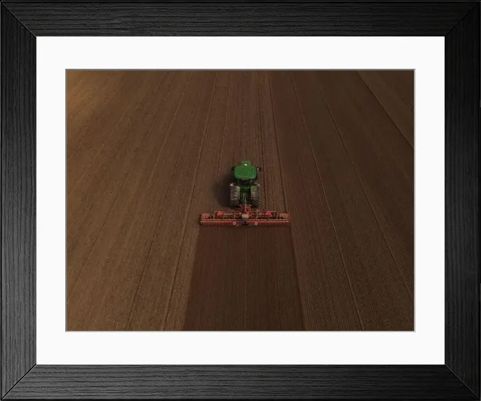 Framed Print : A John Deere tractor, seen from above, cultivates a field in preparation for planting Framed Print : A John Deere tractor, seen from above, cultivates a field in preparation for planting