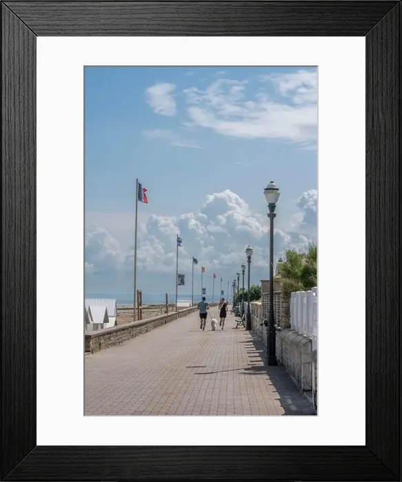 Framed Print : Saint-Aubin-Sur-Mer, France - 07 25 2023: A man and a woman with a white dog are running on the jetty next to the beach Framed Print : Saint-Aubin-Sur-Mer, France - 07 25 2023: A man and a woman with a white dog are running on the jetty next to the beach