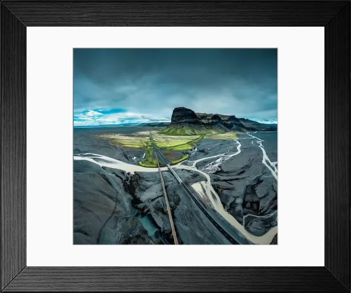 Framed Print : Aerial view of moody rugged volcanic Lomagnupur mountain and highway over glacier river Framed Print : Aerial view of moody rugged volcanic Lomagnupur mountain and highway over glacier river