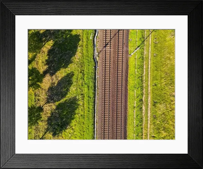 Framed Print : A railroad track with two lanes of tracks passes through nature directly from above as an aerial shot Framed Print : A railroad track with two lanes of tracks passes through nature directly from above as an aerial shot
