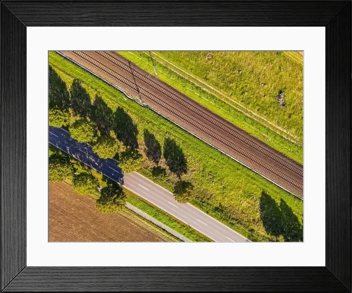 Framed Print : A road, trees and a railroad line directly from above as an aerial view, Germany Framed Print : A road, trees and a railroad line directly from above as an aerial view, Germany