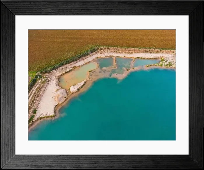 Framed Print : An artificial lake with turquoise water and several pools on the shore next to agricultural fields as an aerial view