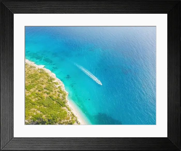 Framed Print : Aerial view of a clear blue sea. A boat leaving a white trail and a sunlit shoreline Framed Print : Aerial view of a clear blue sea. A boat leaving a white trail and a sunlit shoreline