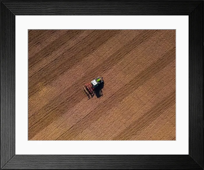 Framed Print : A tractor with plow on a field plowing from the ground directly from above with drone Framed Print : A tractor with plow on a field plowing from the ground directly from above with drone