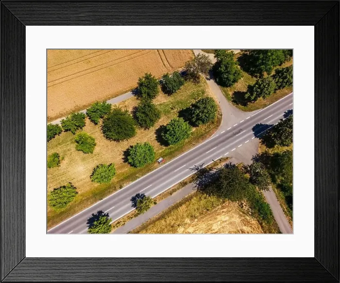 Framed Print : Country road with cycle path next to fields with trees and several dirt tracks in rural countryside Framed Print : Country road with cycle path next to fields with trees and several dirt tracks in rural countryside