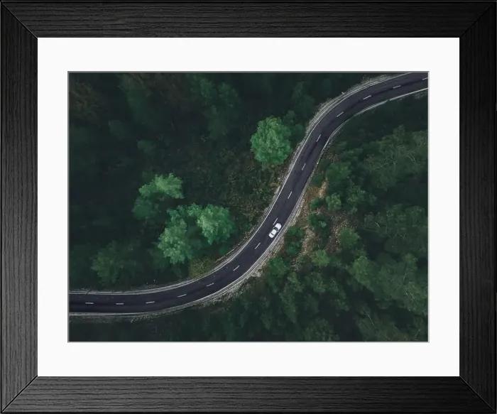 Framed Print : Aerial view taken by drone of a car driving on a forest road in autumn Framed Print : Aerial view taken by drone of a car driving on a forest road in autumn