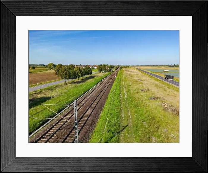 Framed Print : An electric railroad line with tracks next to two roads in a rural area, Germany Framed Print : An electric railroad line with tracks next to two roads in a rural area, Germany