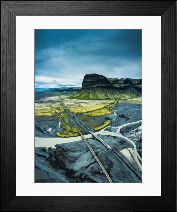 Framed Print : Aerial view of moody rugged volcanic Lomagnupur mountain and highway over glacier river Framed Print : Aerial view of moody rugged volcanic Lomagnupur mountain and highway over glacier river