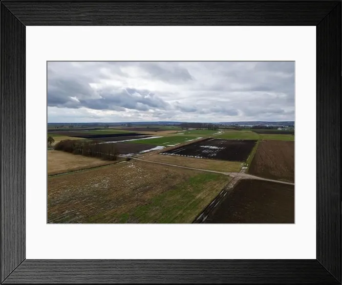 Framed Print : Fields in winter with puddles, mud and taunus in the heavily cloudy background