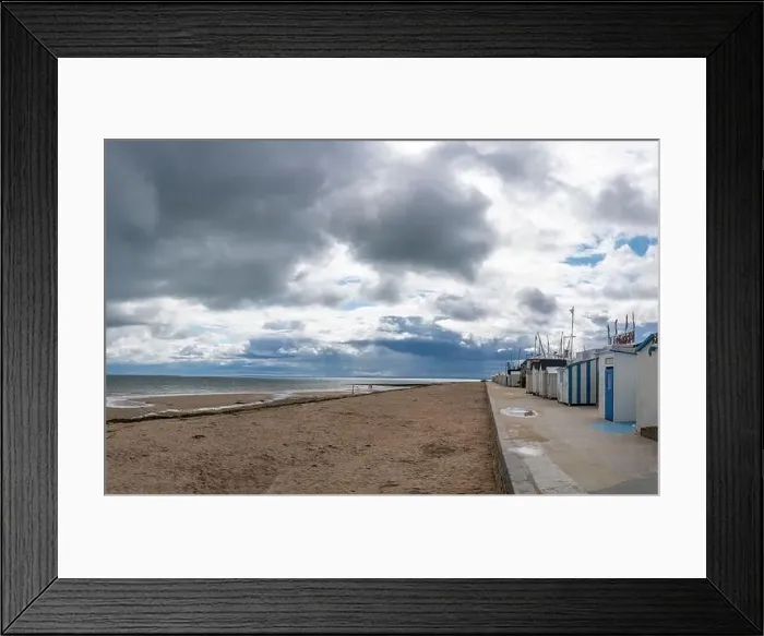 Framed Print : Langrune-Sur-Mer, France - 07 26 2023: View of the sea, the jetty and people walking on the beach with a cloudy sky