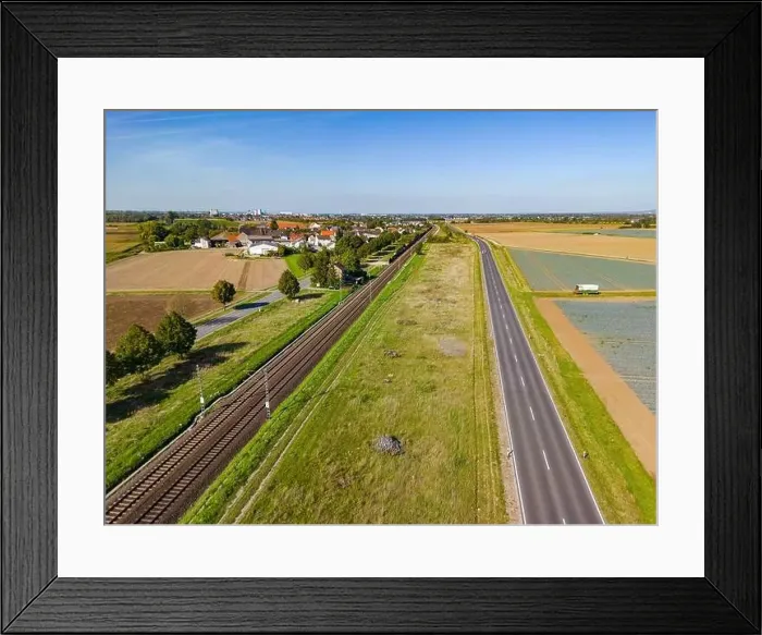 Framed Print : Drone perspective of rural road and railroad line in the countryside, aerial view in Germany Framed Print : Drone perspective of rural road and railroad line in the countryside, aerial view in Germany