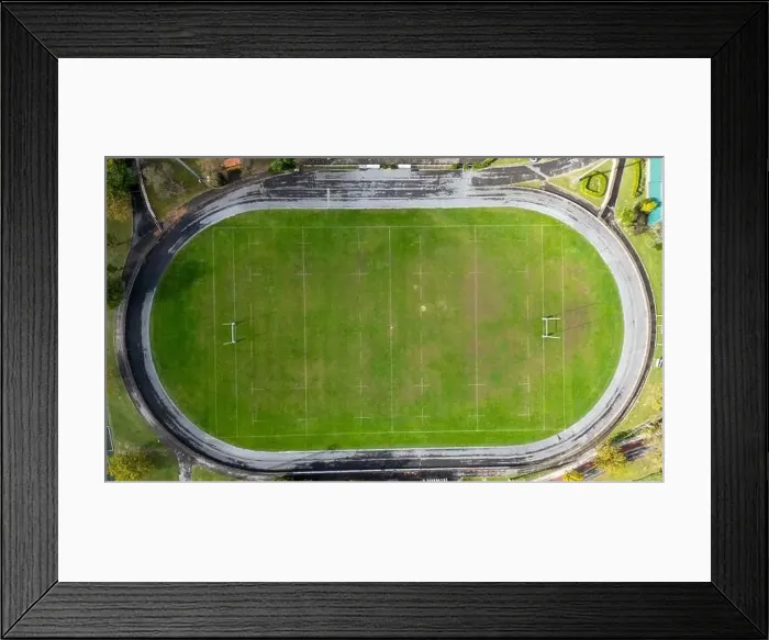 Framed Print : Aerial view of a green rugby pitch with white markings, surrounded by a track Framed Print : Aerial view of a green rugby pitch with white markings, surrounded by a track