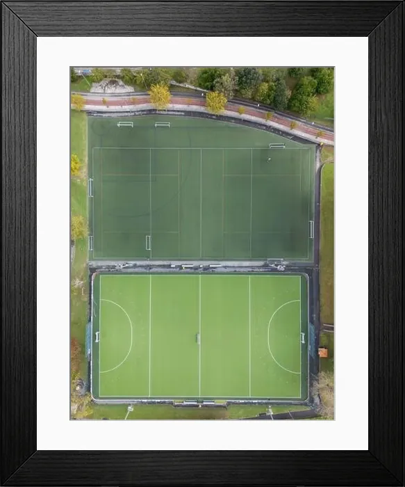 Framed Print : An aerial shot captures two adjacent, empty sports fields with clear markings, surrounded by greenery Framed Print : An aerial shot captures two adjacent, empty sports fields with clear markings, surrounded by greenery