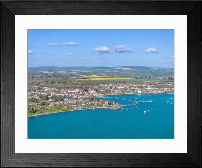 Framed Print : Hampshire town of Emsworth from above. View looking East along the coastline. Farmland and hills beyond the town Framed Print : Hampshire town of Emsworth from above. View looking East along the coastline. Farmland and hills beyond the town