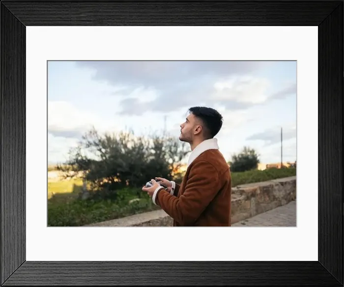 Framed Print : Young man using a drone to photograph and record the landscape Framed Print : Young man using a drone to photograph and record the landscape