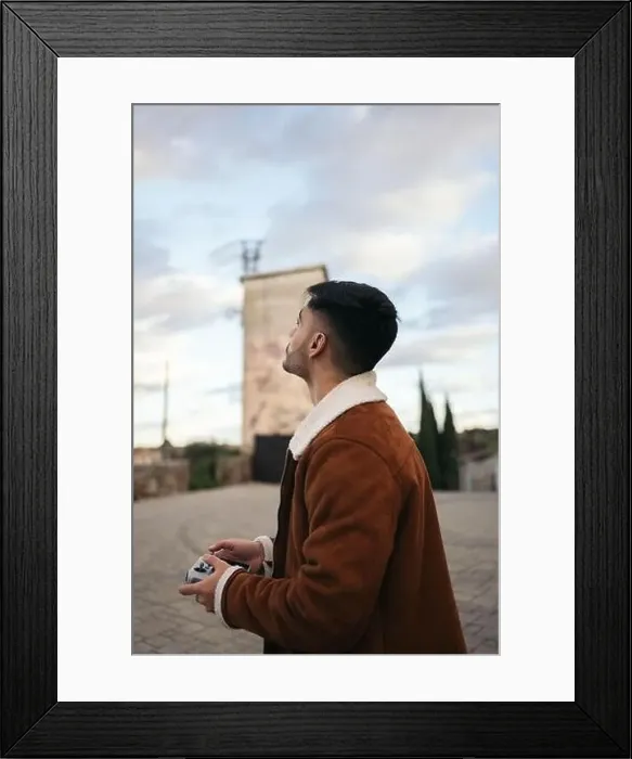 Framed Print : Young man using a drone to photograph and record the landscape Framed Print : Young man using a drone to photograph and record the landscape