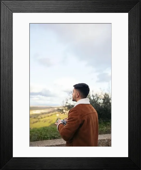 Framed Print : Young man using a drone to photograph and record the landscape Framed Print : Young man using a drone to photograph and record the landscape