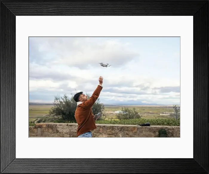 Framed Print : Young man using a drone to record and photograph the landscape Framed Print : Young man using a drone to record and photograph the landscape