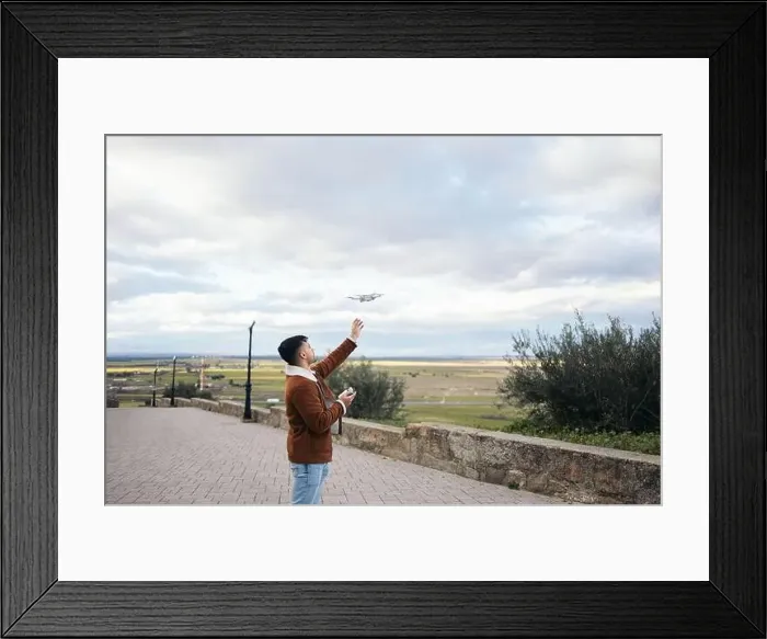 Framed Print : Young man using a drone to record and photograph the landscape Framed Print : Young man using a drone to record and photograph the landscape