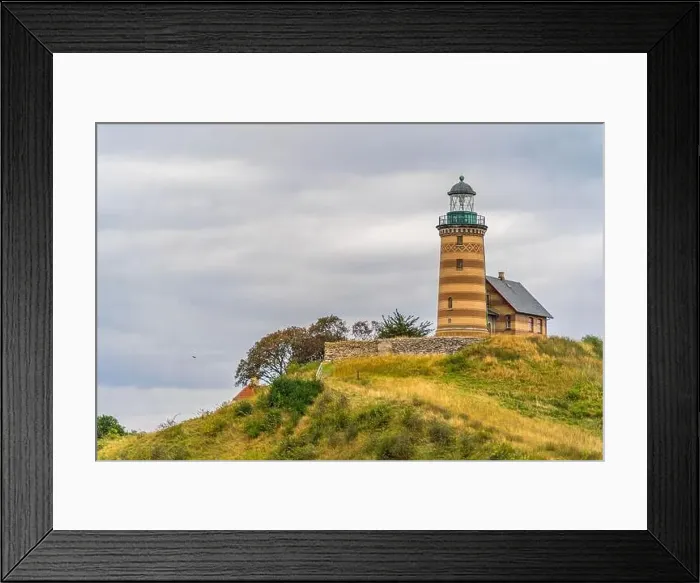 Framed Print : Atop a grassy hill stands a majestic lighthouse against the backdrop of a clear sky Framed Print : Atop a grassy hill stands a majestic lighthouse against the backdrop of a clear sky