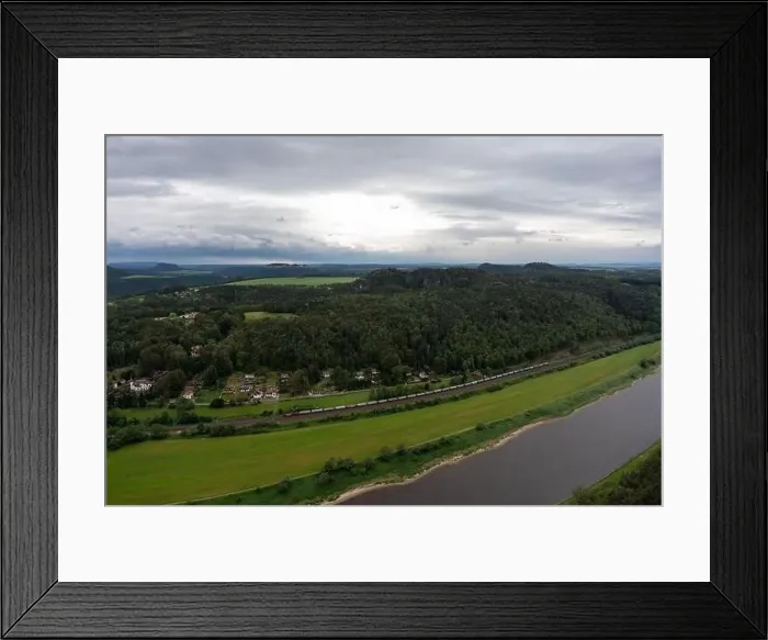Framed Print : A train is traveling down a train track next to a river