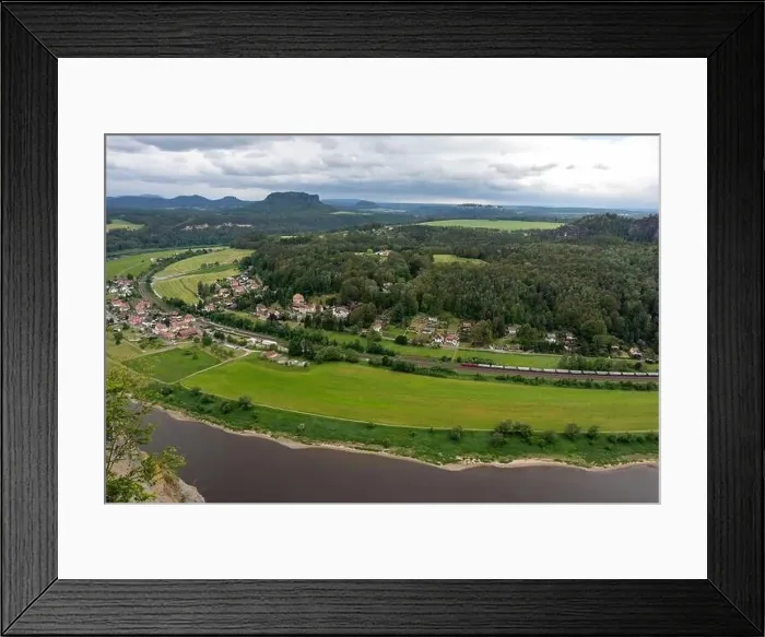 Framed Print : A view of a town and a river with a train passing by. The town is surrounded by a green field and the river is brown Framed Print : A view of a town and a river with a train passing by. The town is surrounded by a green field and the river is brown