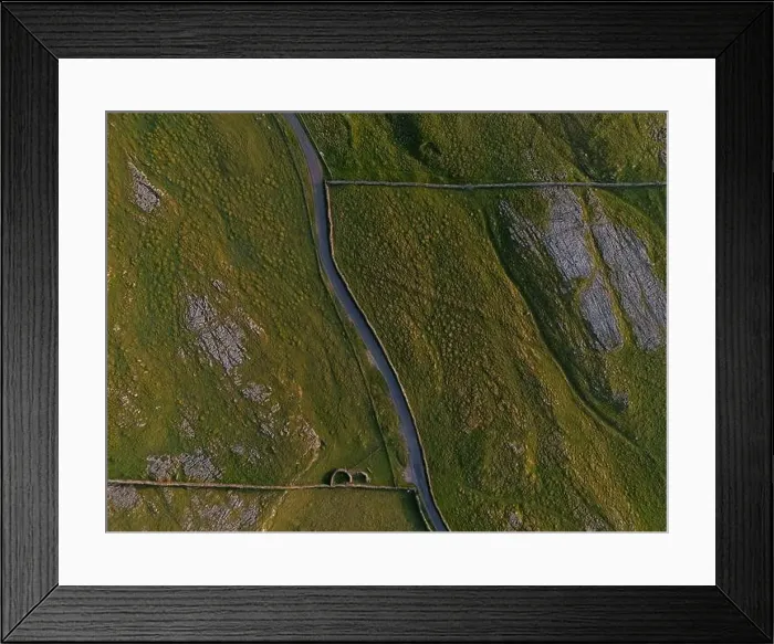 Framed Print : A top-down shot capturing a serpentine road meandering through a rugged, natural landscape with textured terrain